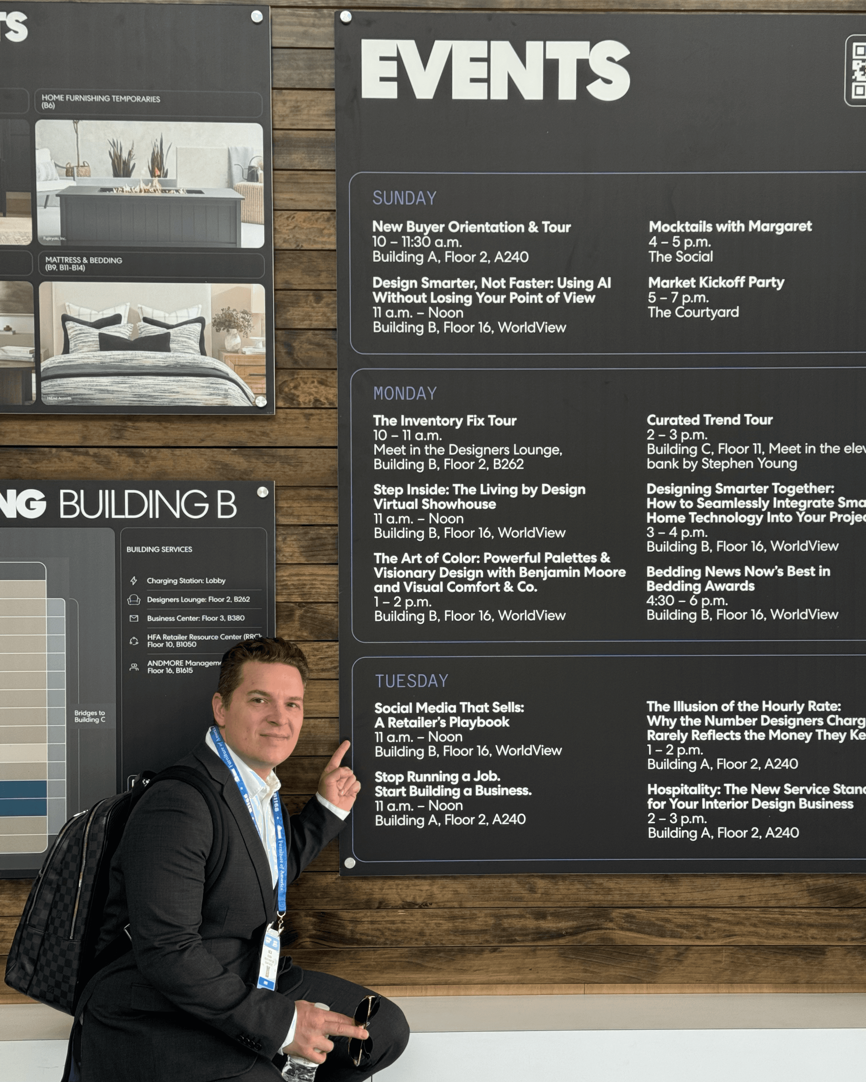 Man in a suit points to a large black events schedule board listing daily seminars.